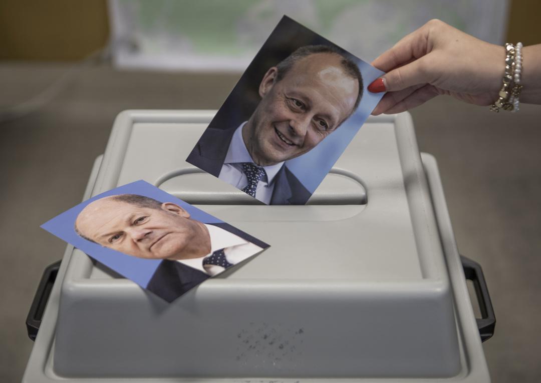 Wahlurne mit Fotos von Olaf Scholz (l.) und Friedrich Merz