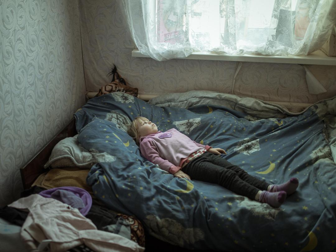 Die neunjährige Angelina auf ihrem Bett im ukrainischen Dorf Borshchiwka, das unter russischer Besatzung war. Das Mädchen leidet seitdem unter Angststörungen