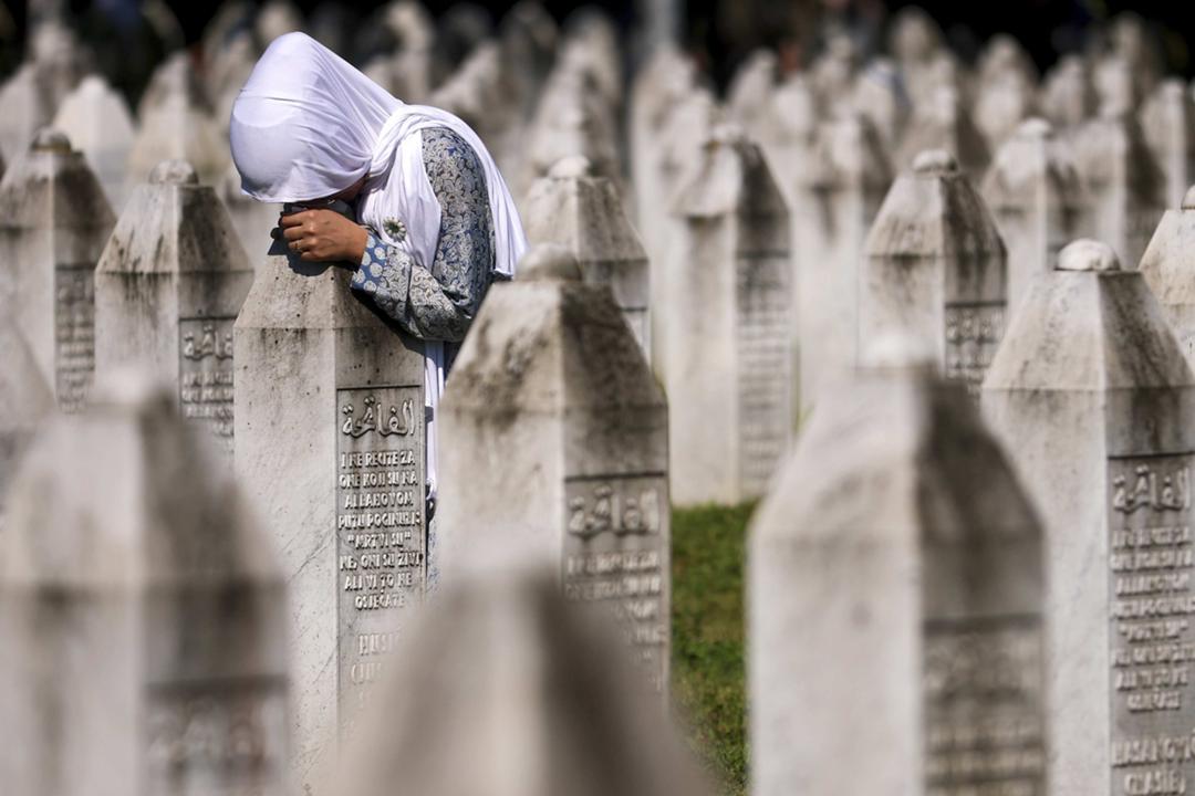Eine muslimische Frau trauert neben am Grab ihrer Verwandten bei der Gedenkstätte Srebrenica im Juli 2024