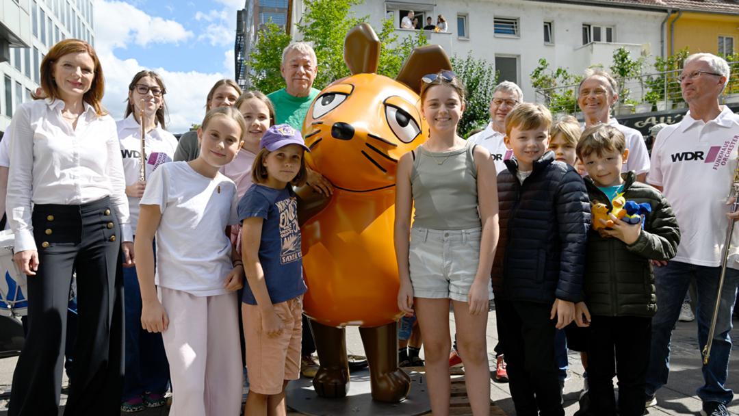 Intendantin Katrin Vernau (links), Christoph Biemann (hinten), Musiker des WDR Funkhausorchesters und Kinder mit der zurückgekehrten Mausfigur