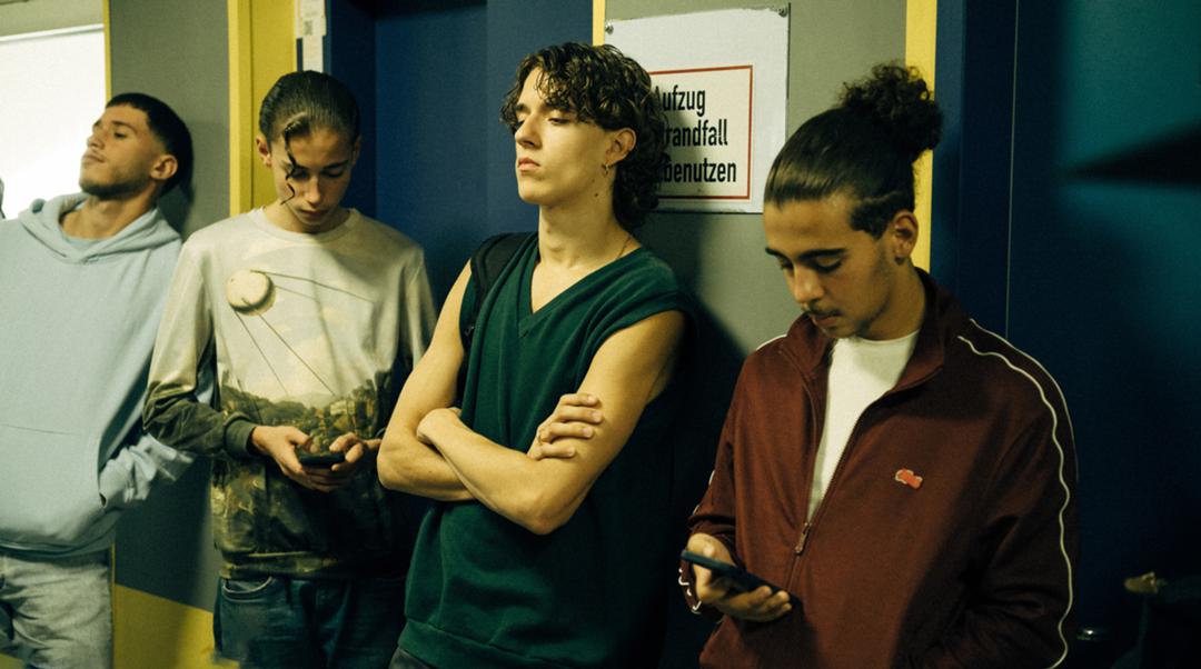 Flavio (Marven Gabriel Suarez-Brinkert, 2. v. re.) wartet vor dem Lehrerzimmer auf ein Verhör mit der Polizei.