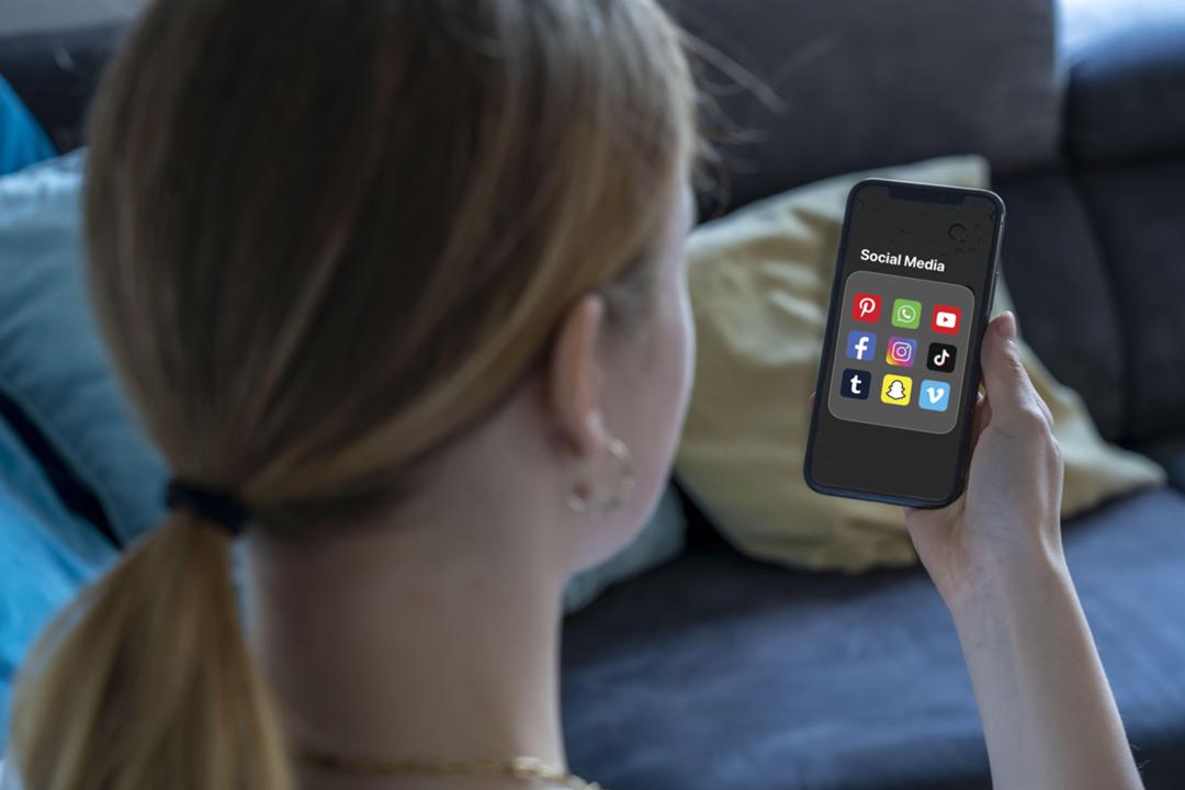 Ein 14 Jahre altes Mädchen nutzt diverse Social-Media-Plattformen auf dem Handy