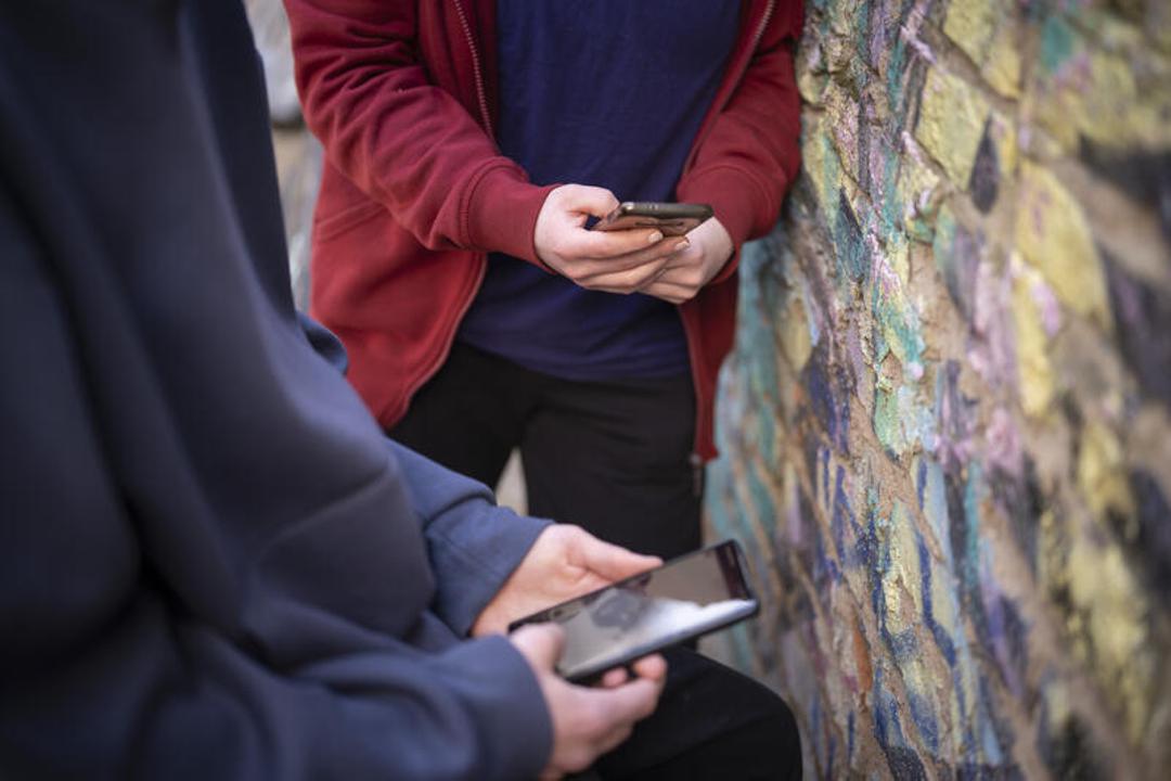 Jugendliche schauen in ihre Handys.