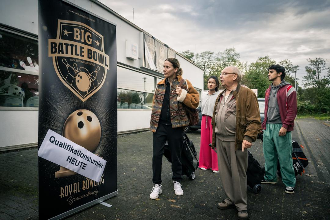 "Die Abräumer" stehen vor der Bowlinghalle und dem großen Werbebanner "Big Battle Bowl - Qualifikationsturnier heute"