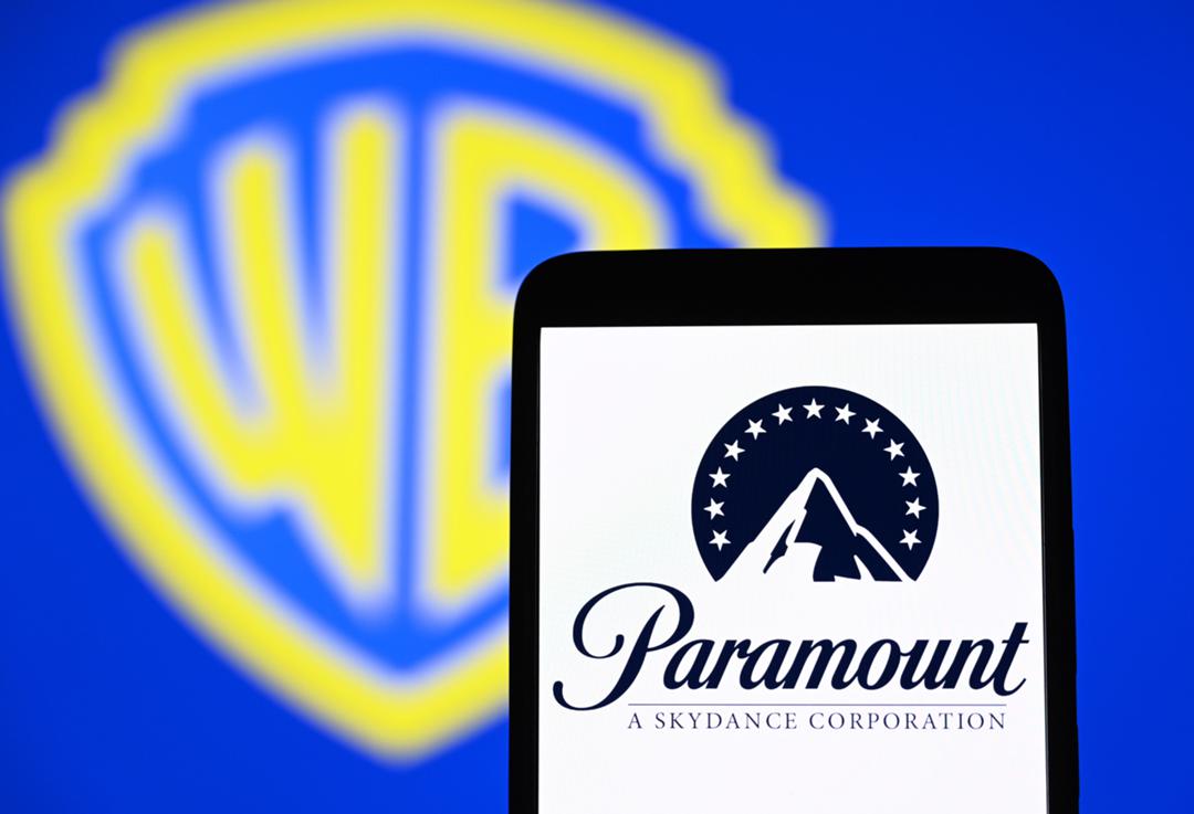 Paramount-Skydance-Logo auf einem Smartphone und Warner-Logo im Hintergrund
